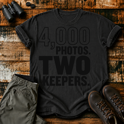 4,000 Photos Two Keepers Bird Photography Tee in Black, centered front design on a birdwatching flat-lay mockup
