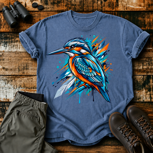 Abstract Kingfisher Splash Tee in Blue Jean, centered front design on a birdwatching flat-lay mockup