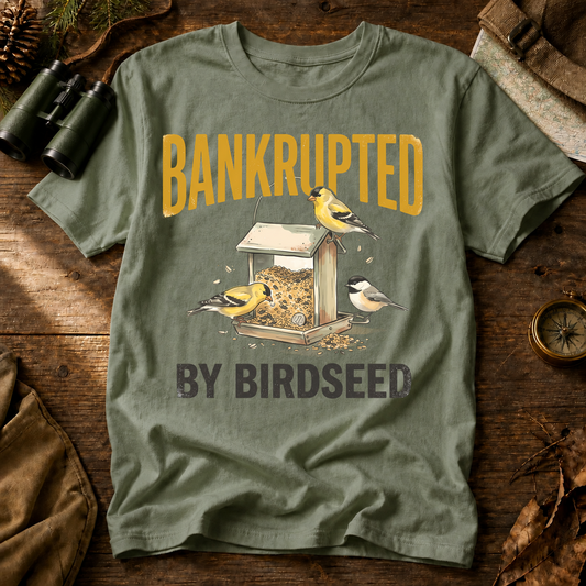 Bankrupted by Birdseed Backyard Birds Tee in Bay, centered front design on a birdwatching flat-lay mockup