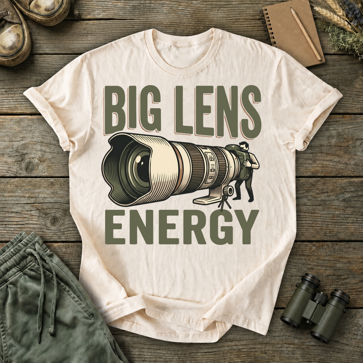 Big Lens Energy Bird Photography Tee in Ivory, centered front design on a birdwatching flat-lay mockup
