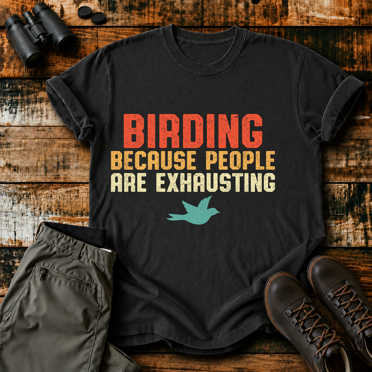 Birding Because People Are Exhausting Tee in Black, centered front design on a birdwatching flat-lay mockup