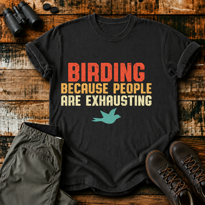 Birding Because People Are Exhausting Tee in Black, centered front design on a birdwatching flat-lay mockup