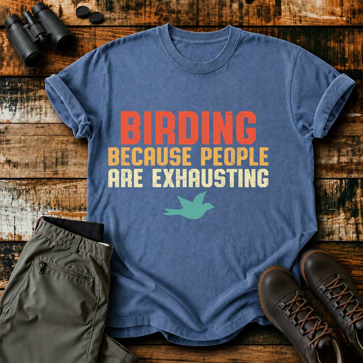 Birding Because People Are Exhausting Tee in Blue Jean, centered front design on a birdwatching flat-lay mockup