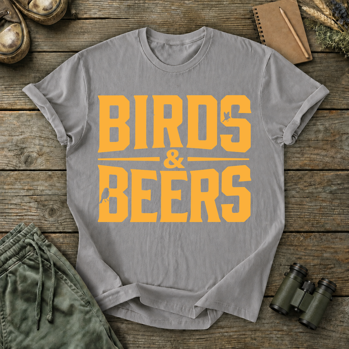 Birds & Beers Tee in Grey, centered front design on a birdwatching flat-lay mockup