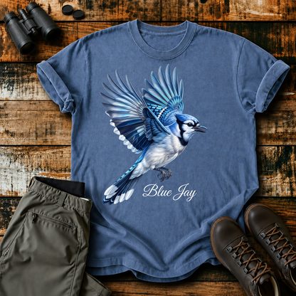 Blue Jay in Flight Tee in Blue Jean, centered front design on a birdwatching flat-lay mockup