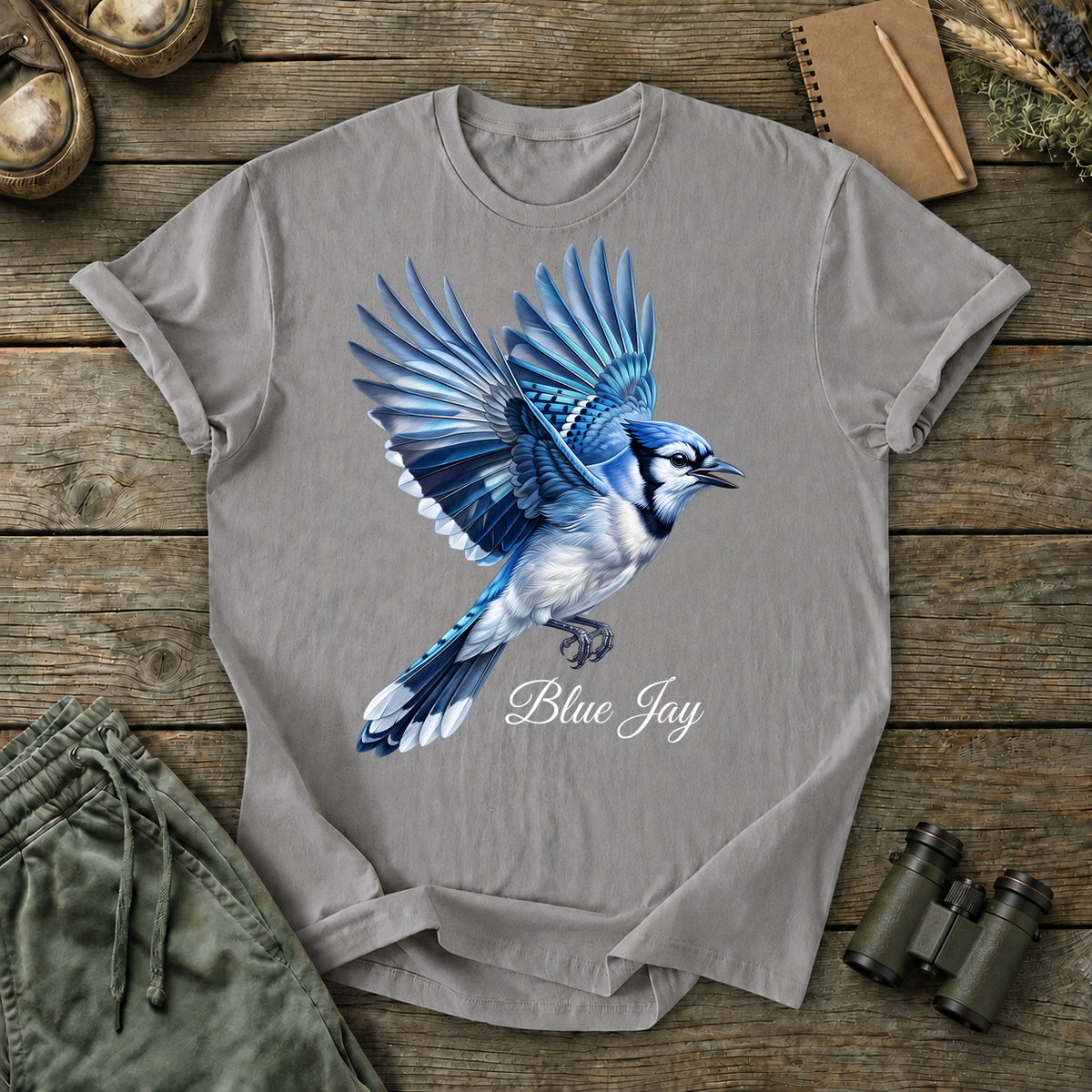 Blue Jay in Flight Tee in Grey, centered front design on a birdwatching flat-lay mockup