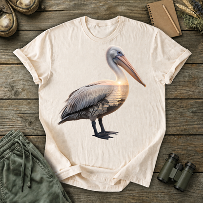 Brown Pelican Portrait Tee in Ivory, centered front design on a birdwatching flat-lay mockup