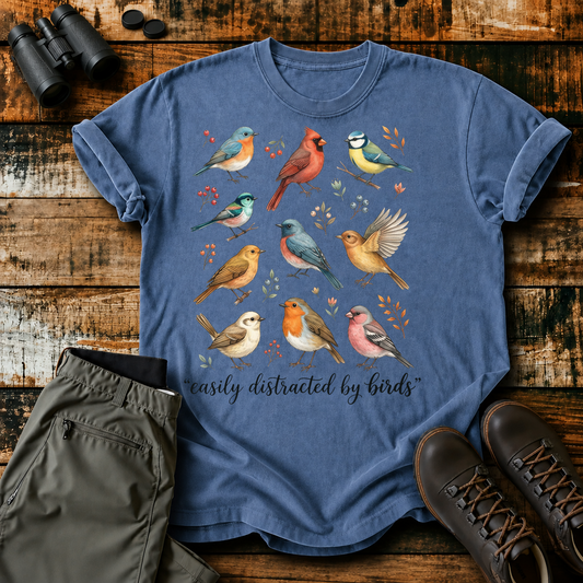 Easily Distracted by Birds Colorful Flock Tee in Blue Jean, centered front design on a birdwatching flat-lay mockup