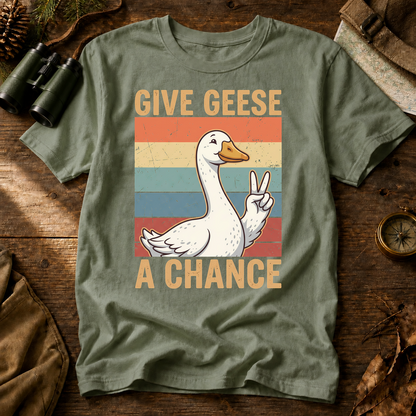 Give Geese a Chance Tee in Bay, centered front design on a birdwatching flat-lay mockup