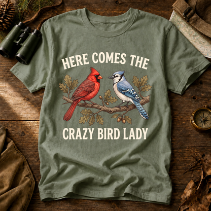 Here Comes the Crazy Bird Lady Tee in Bay, centered front design on a birdwatching flat-lay mockup