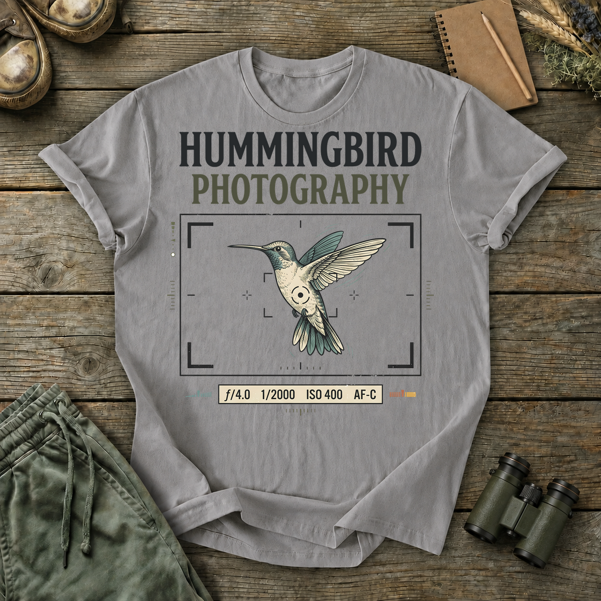 Hummingbird Photography Camera Settings Tee in Grey, centered front design on a birdwatching flat-lay mockup