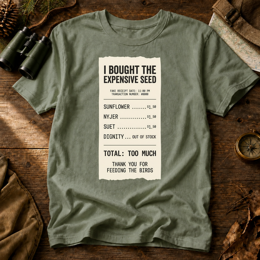 I Bought the Expensive Seed Receipt Tee in Bay, centered front design on a birdwatching flat-lay mockup