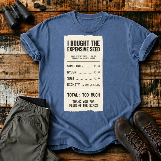 I Bought the Expensive Seed Receipt Tee in Blue Jean, centered front design on a birdwatching flat-lay mockup