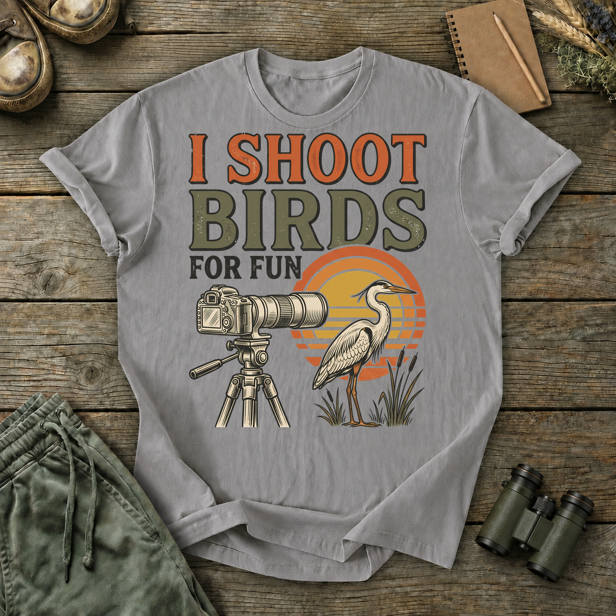 I Shoot Birds for Fun Photography Tee in Grey, centered front design on a birdwatching flat-lay mockup