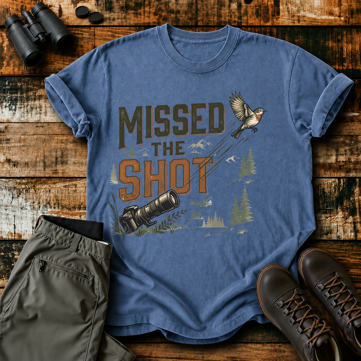 Missed the Shot Bird Photography Tee in Blue Jean, centered front design on a birdwatching flat-lay mockup