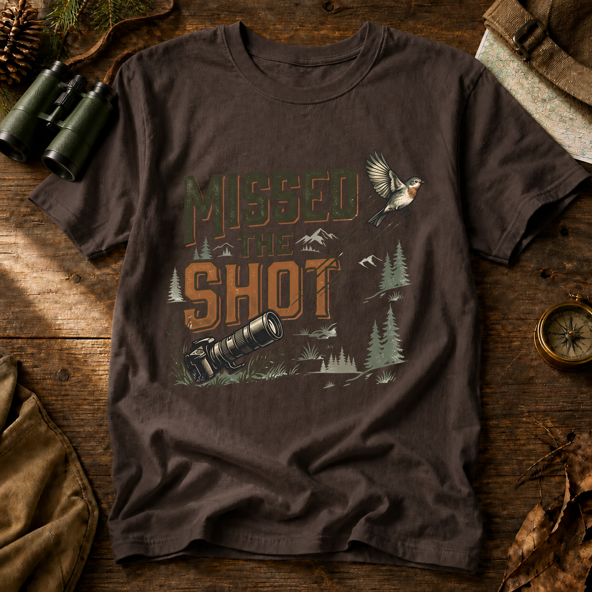 Missed the Shot Bird Photography Tee in Espresso, centered front design on a birdwatching flat-lay mockup