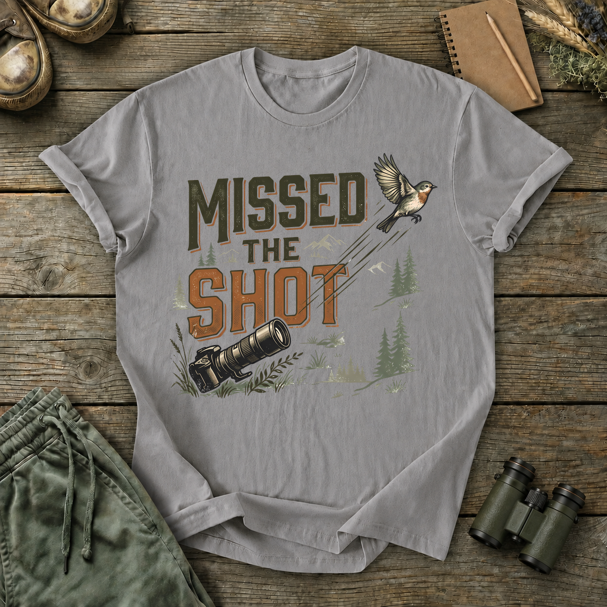 Missed the Shot Bird Photography Tee in Grey, centered front design on a birdwatching flat-lay mockup