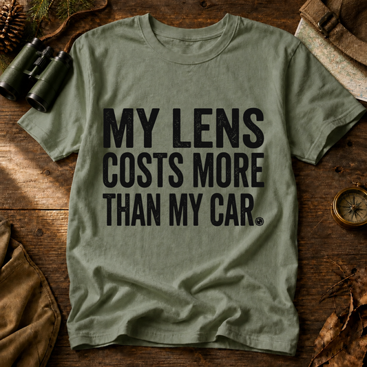 My Lens Costs More Than My Car Tee in Bay, centered front design on a birdwatching flat-lay mockup