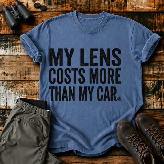 My Lens Costs More Than My Car Tee in Blue Jean, centered front design on a birdwatching flat-lay mockup