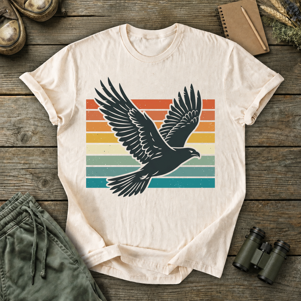 Retro Flying Bird Stripes Tee in Ivory, centered front design on a birdwatching flat-lay mockup