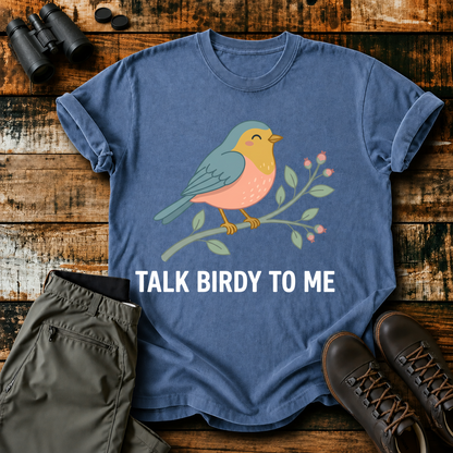 Talk Birdy to Me Songbird Tee in Blue Jean, centered front design on a birdwatching flat-lay mockup