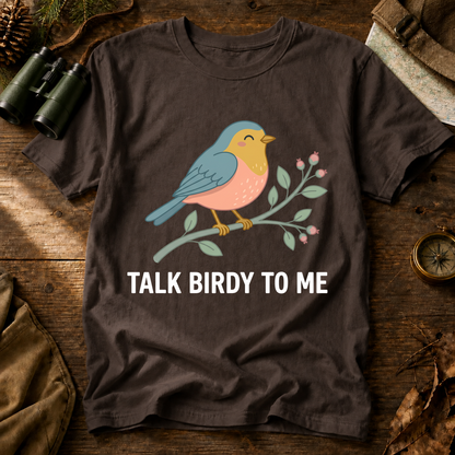 Talk Birdy to Me Songbird Tee in Espresso, centered front design on a birdwatching flat-lay mockup