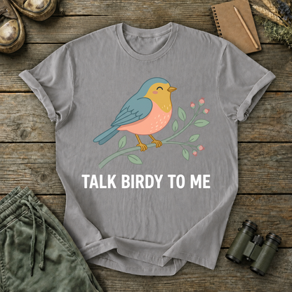 Talk Birdy to Me Songbird Tee in Grey, centered front design on a birdwatching flat-lay mockup