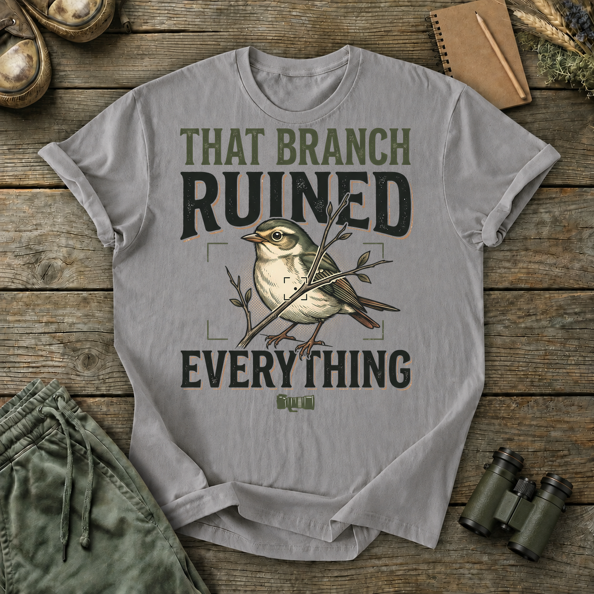 That Branch Ruined Everything Bird Photography Tee in Grey, centered front design on a birdwatching flat-lay mockup