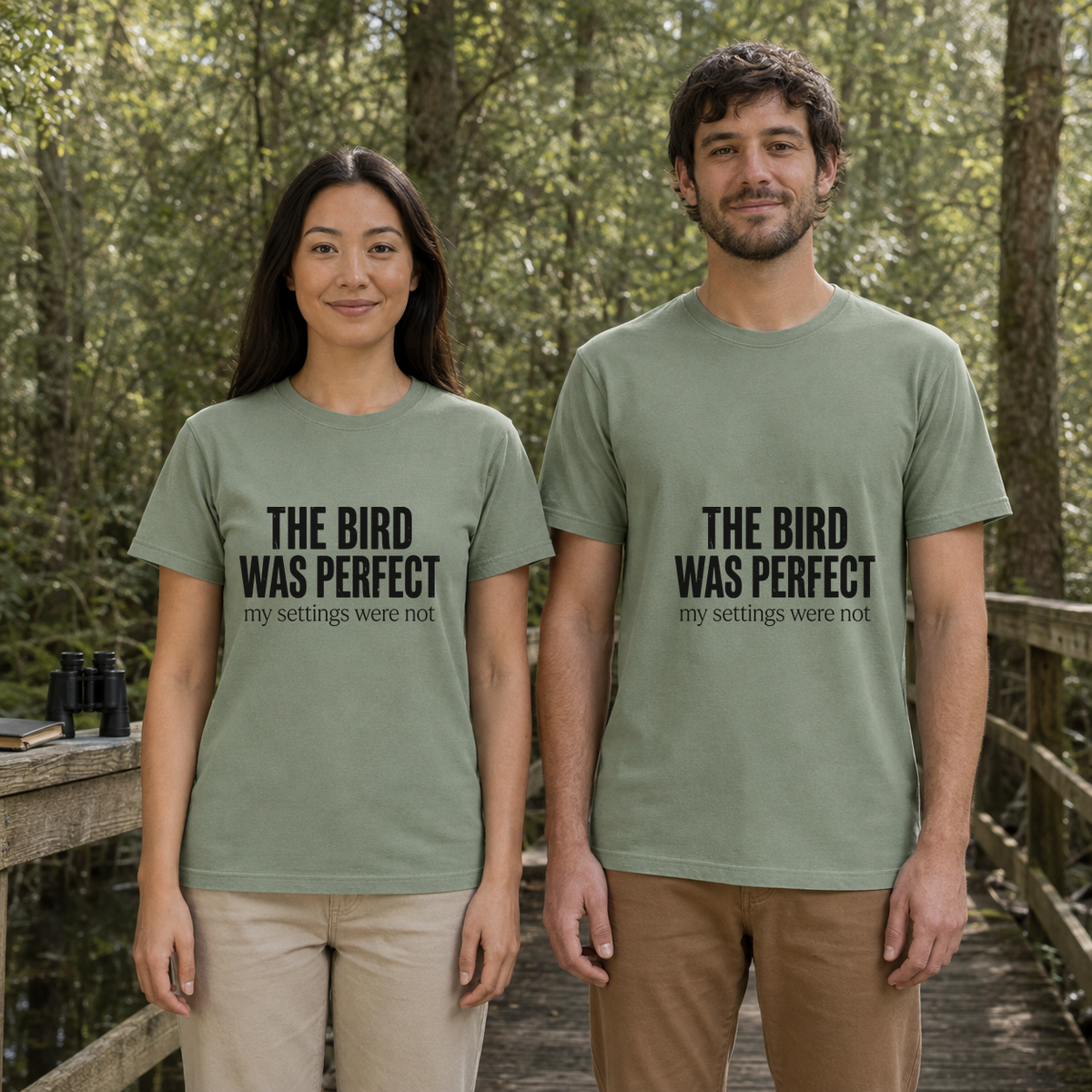 Female and male models wearing the The Bird Was Perfect My Settings Were Not Tee in Bay, with the artwork centered on both shirts