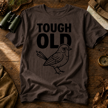 Tough Old Bird Tee in Espresso, centered front design on a birdwatching flat-lay mockup
