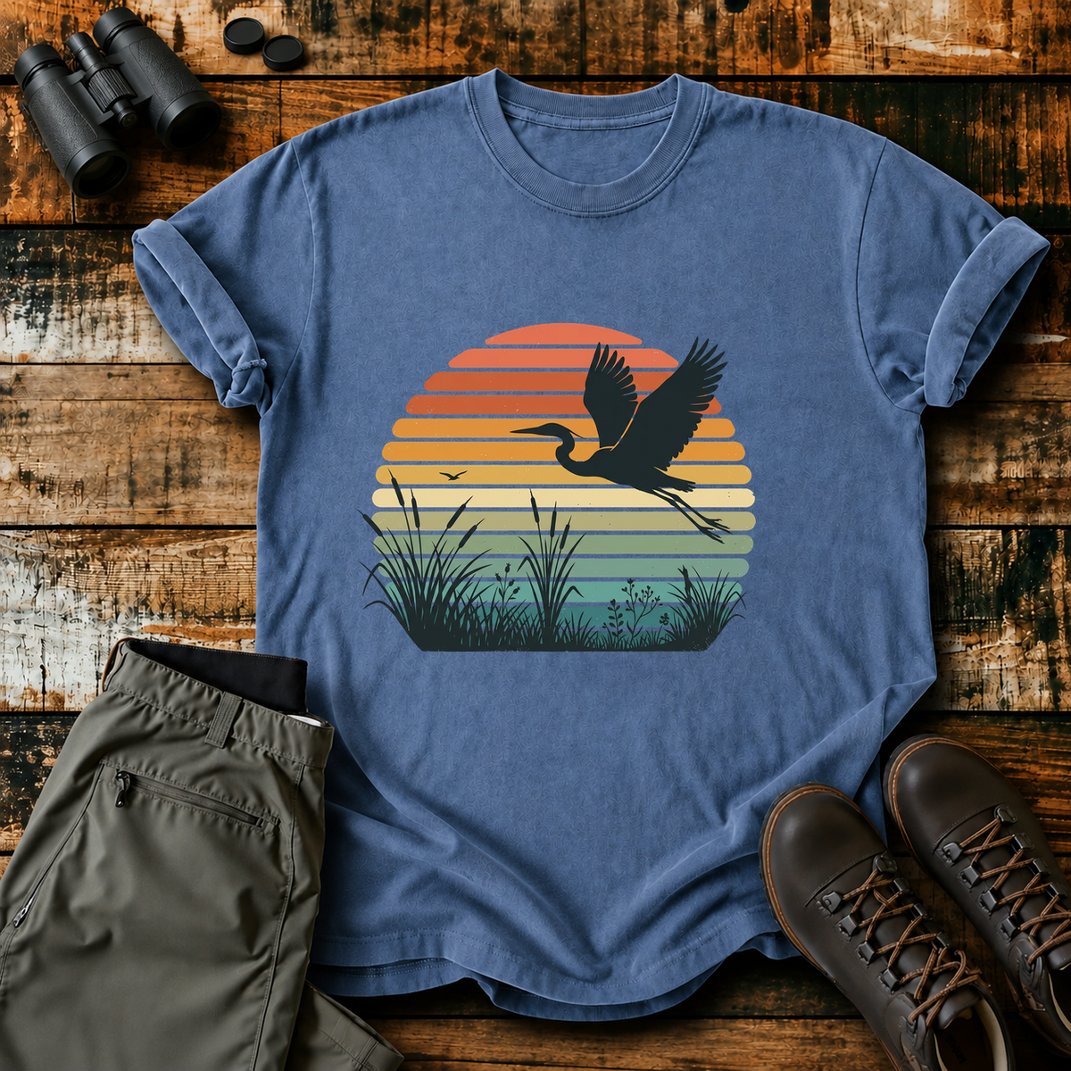 Vintage Sunset Marsh Bird Tee in Blue Jean, centered front design on a birdwatching flat-lay mockup