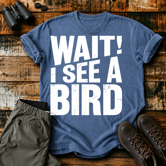 Wait I See a Bird Tee in Blue Jean, centered front design on a birdwatching flat-lay mockup