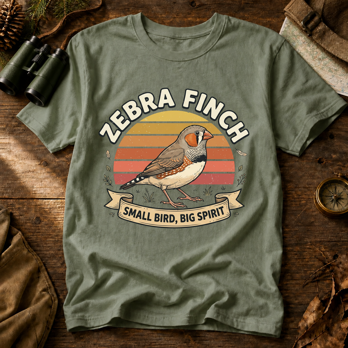 Zebra Finch Small Bird Big Spirit Tee in Bay, centered front design on a birdwatching flat-lay mockup
